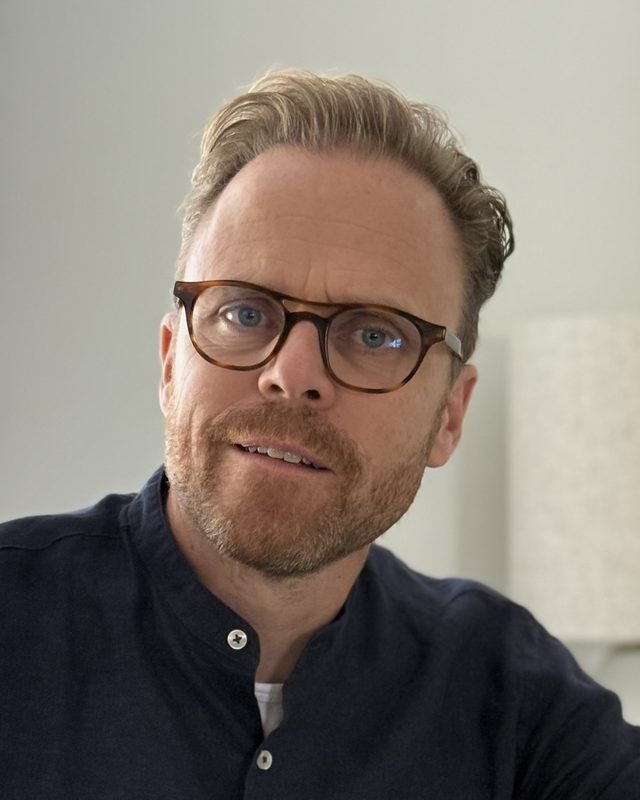 Bart van der Looij aan een marmeren tafel, met zijn telefoon in de hand.